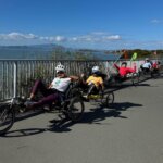 Cyclists in recumbent tandem cycles wave and flash peace signs on the Bay Trail.