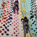 For youth with low vision, the routes with bright pink and yellow holds offer better contrast and visibility. One of the girls had long decorated acrylic nails and surprised us by climbing very well. This is truly adaptive indoor rock climbing.